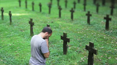 stock-footage-man-praying-over-a-cross-and-grave-at-the-memorial-cemetery